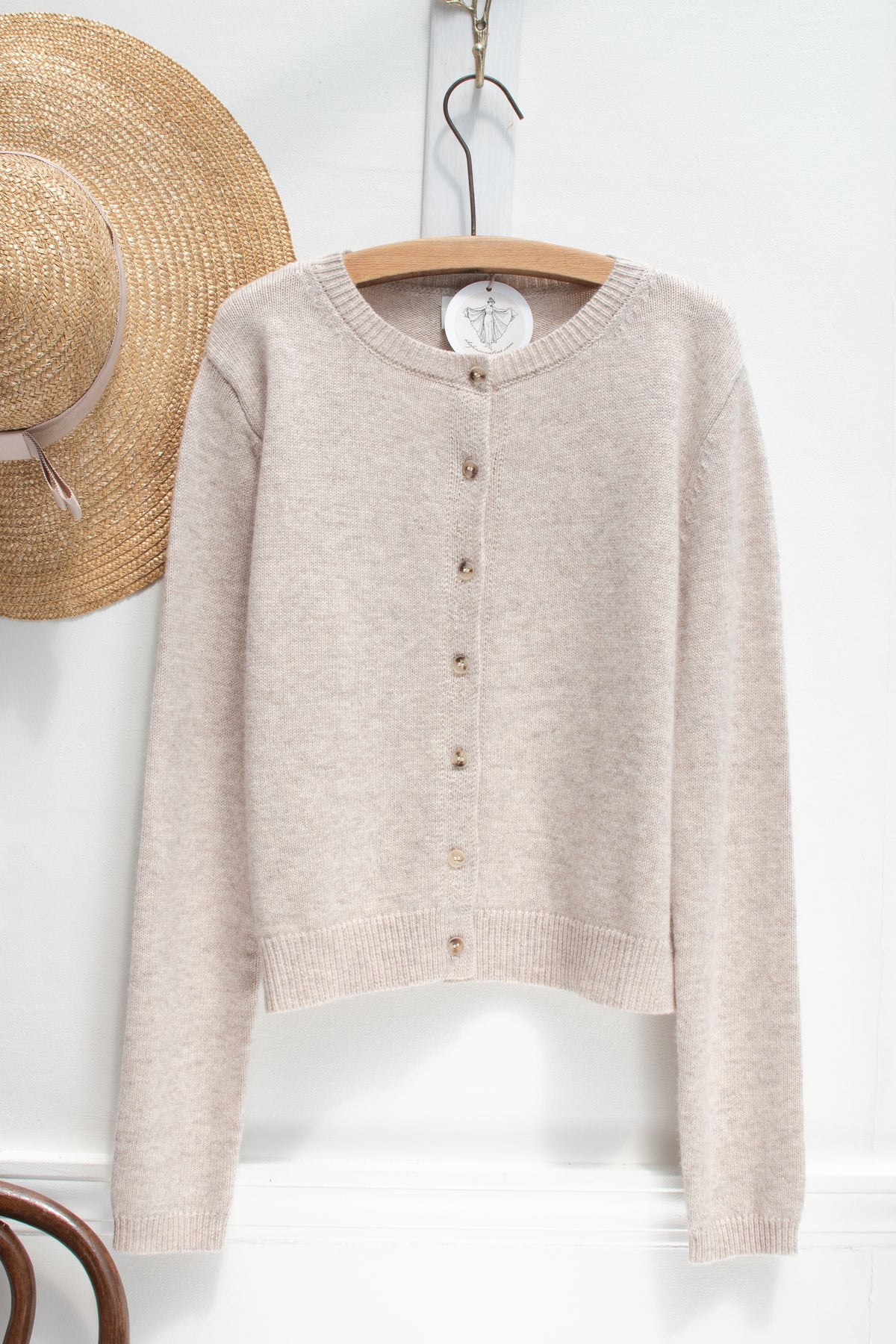 Beige knit cardigan with a round neckline shown on a hanger, front view.