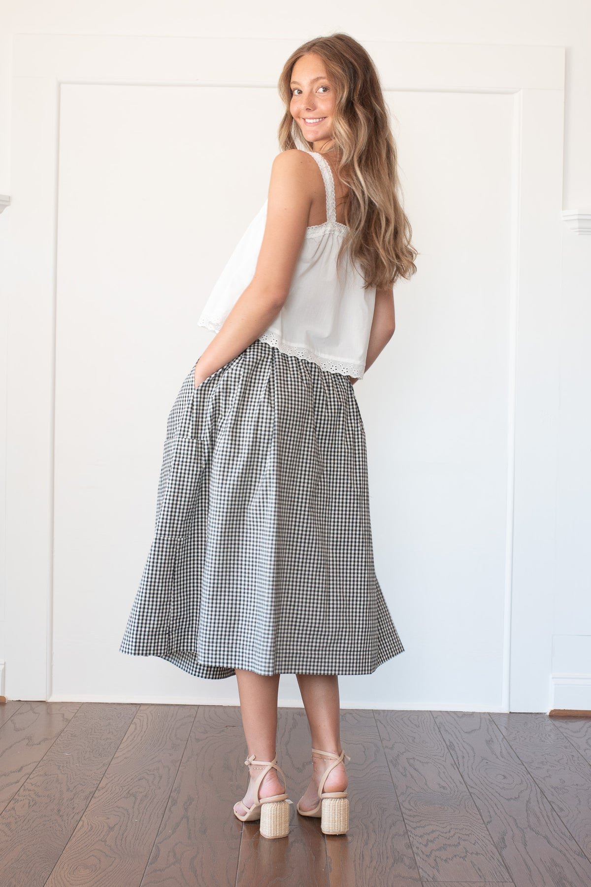 Black and white gingham cotton midi skirt with deep patch pockets, back view on model.