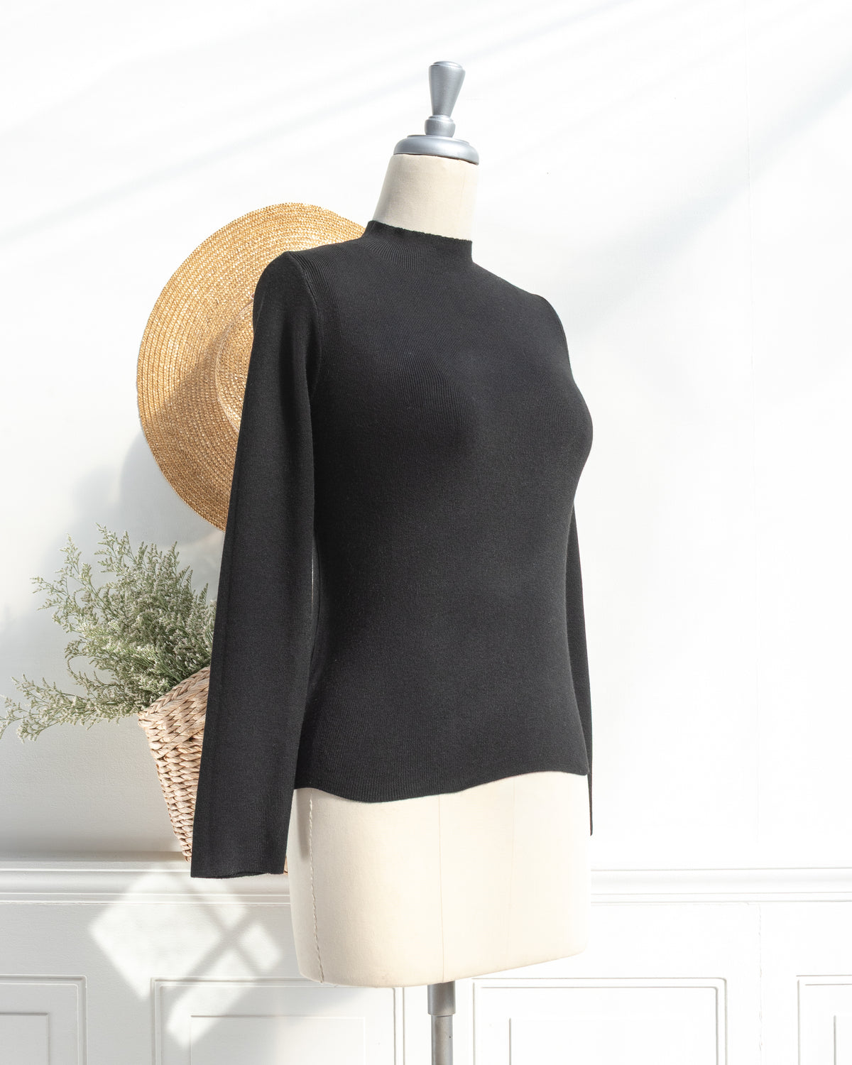 Black knit top with mock neck and long sleeves on a mannequin, classic fall season, three quarter view.