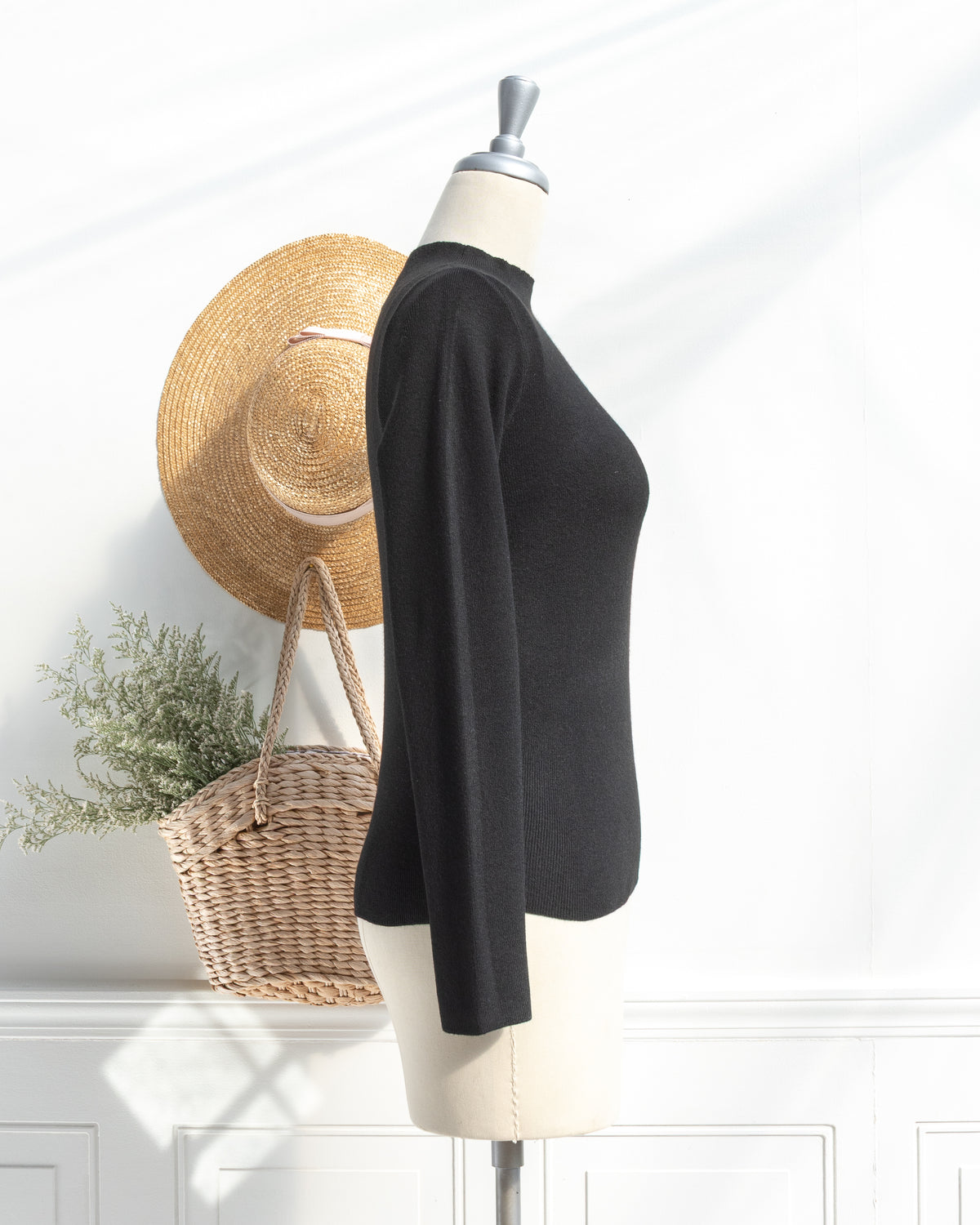 Black lightweight knit top with mock neck and long sleeves on a mannequin, feminine style, side view.