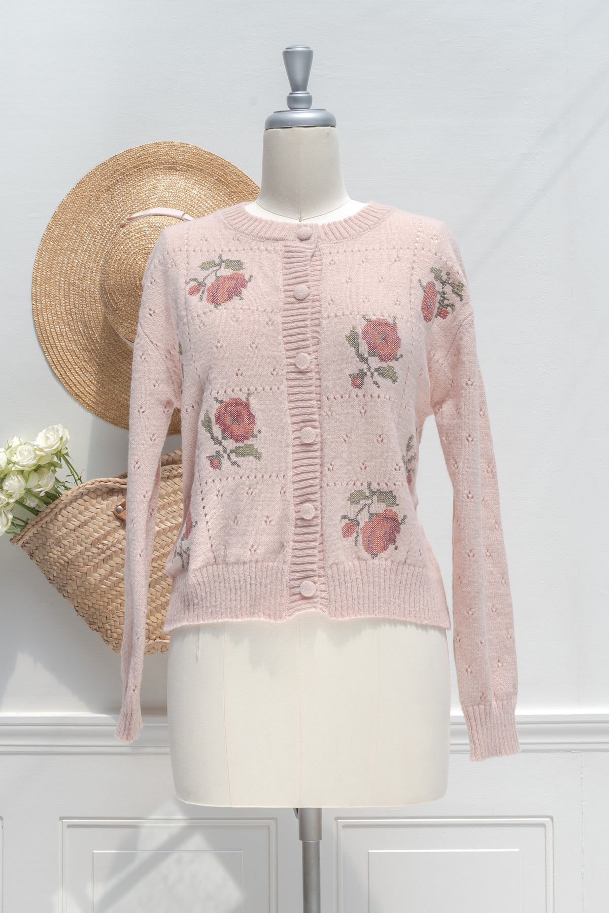 Blush pink cardigan with rose embroidery displayed on a mannequin, front view.