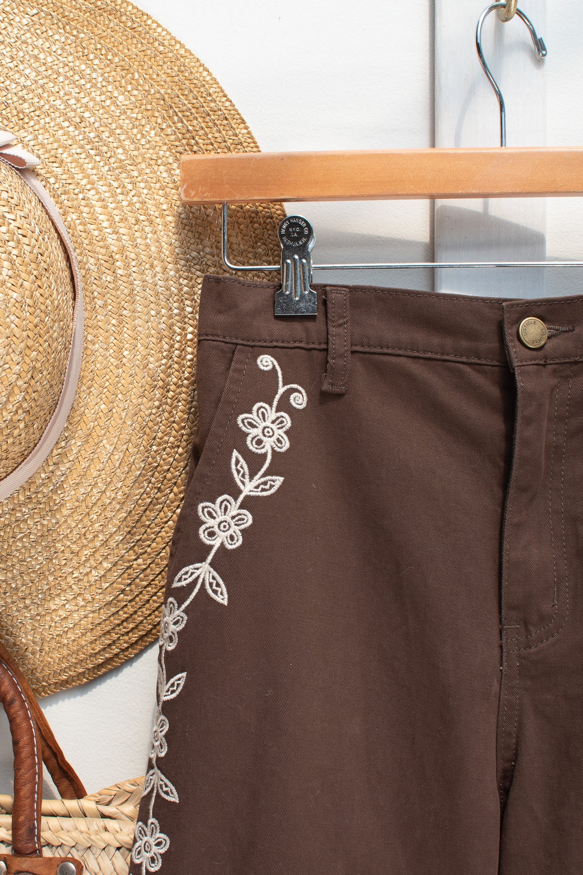 Detail of the floral embroidery and waistband on the brown cotton denim pants.