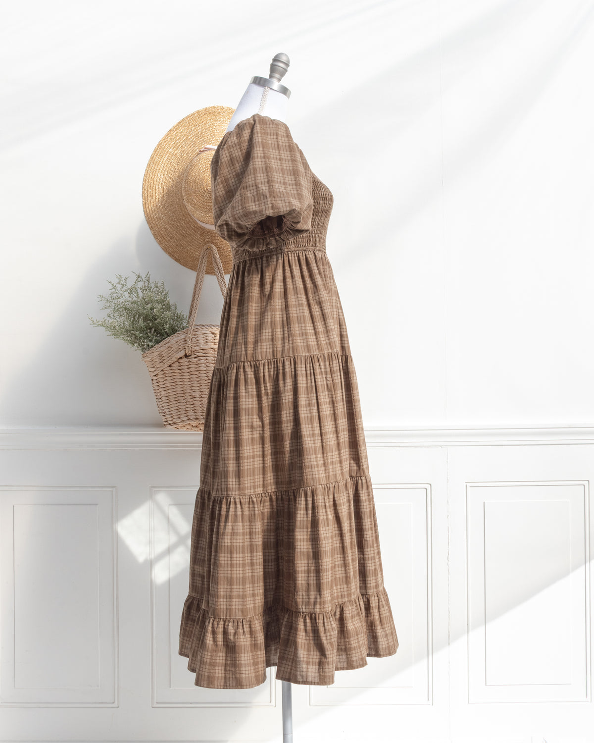 Brown plaid cotton midi dress with puff sleeves and tiered skirt on a mannequin, French girl style, side view.