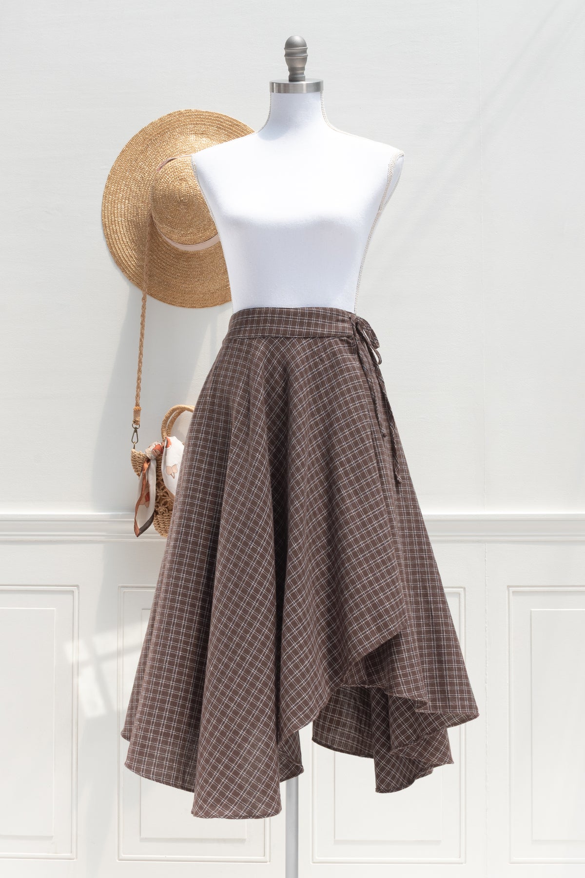 Brown plaid cotton wrap skirt with an asymmetrical hem, a French girl essential shown on a mannequin, front view.