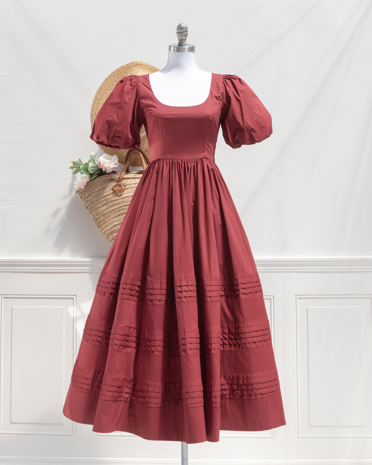 Front view of the Felicity Dress on a dress form, a feminine burgundy cotton midi dress with a scoop neck, puff sleeves, and tiered pintuck skirt.