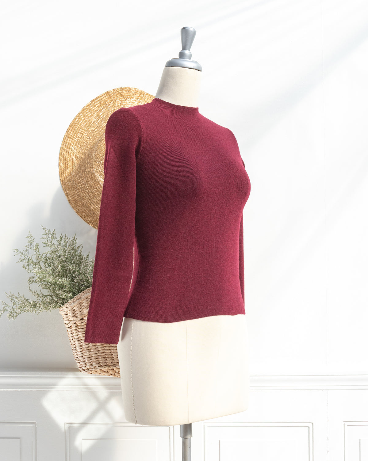 Burgundy knit top with mock neck and long sleeves on a mannequin, classic fall season, three quarter view.