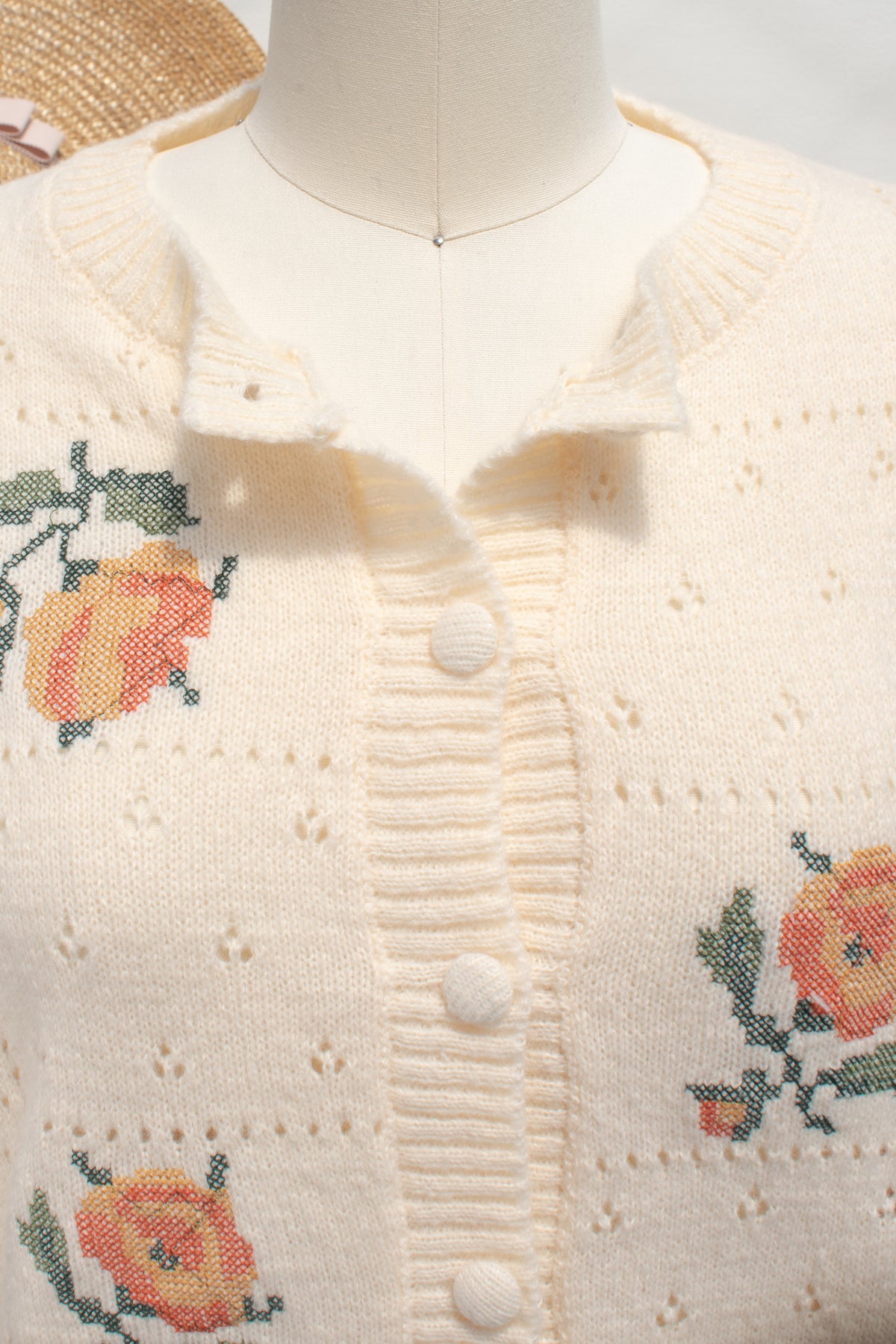 Buttercream knit rose cardigan button placket and ruffled collar shown in close detail.