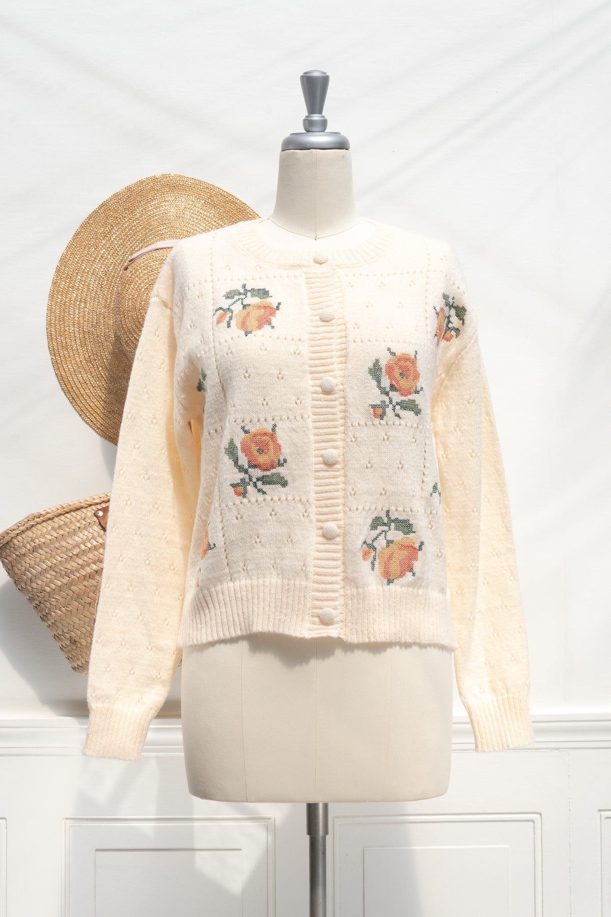 Buttercream knit rose cardigan with floral embroidery on a mannequin, front view.