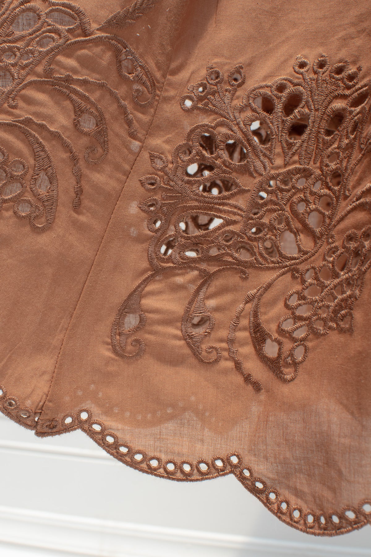 Close up of the cutwork floral embroidery and scalloped hem on the skirt.