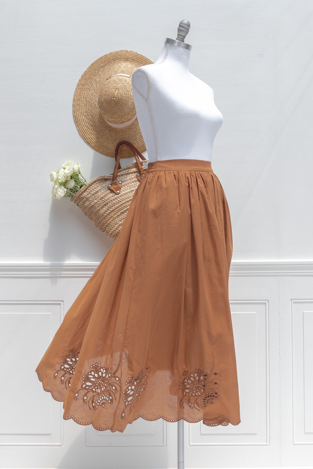 Chestnut cotton midi skirt with embroidered hem, shown on a mannequin, three quarter view.