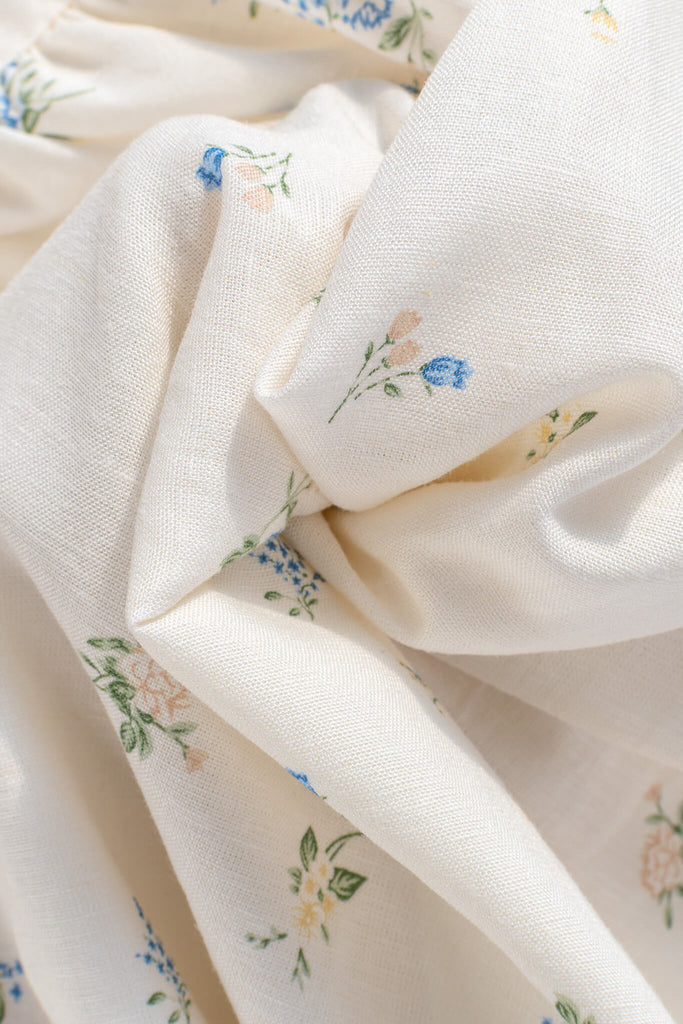 fabric showing texture and small blue, green, and orange tiny floral details. 