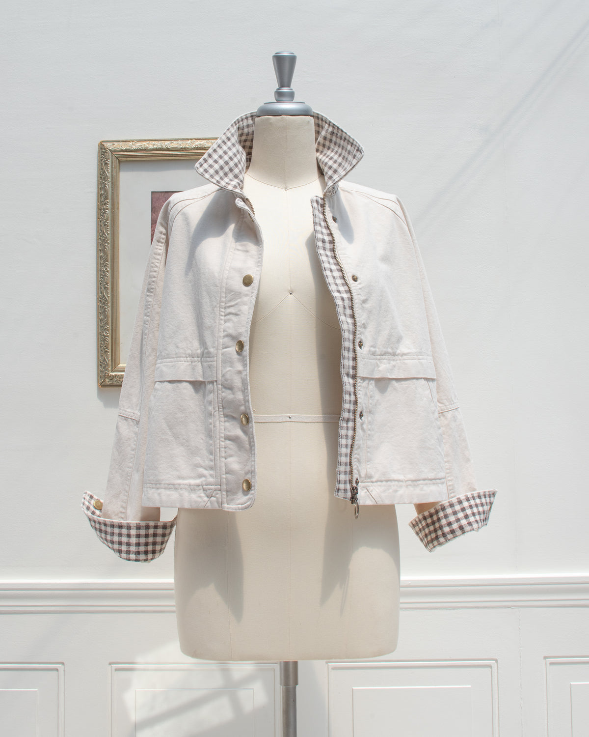 Cream cotton chore jacket worn open to show the zipper and gingham placket, mannequin front view.