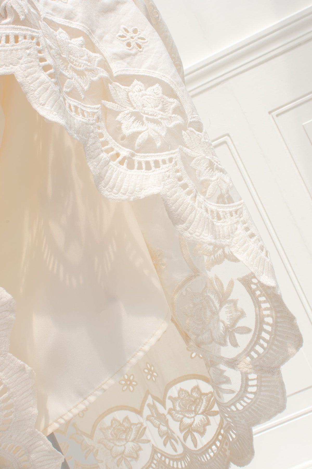 Cream cotton eyelet close up with rose cutwork clusters and lace trimmed. 