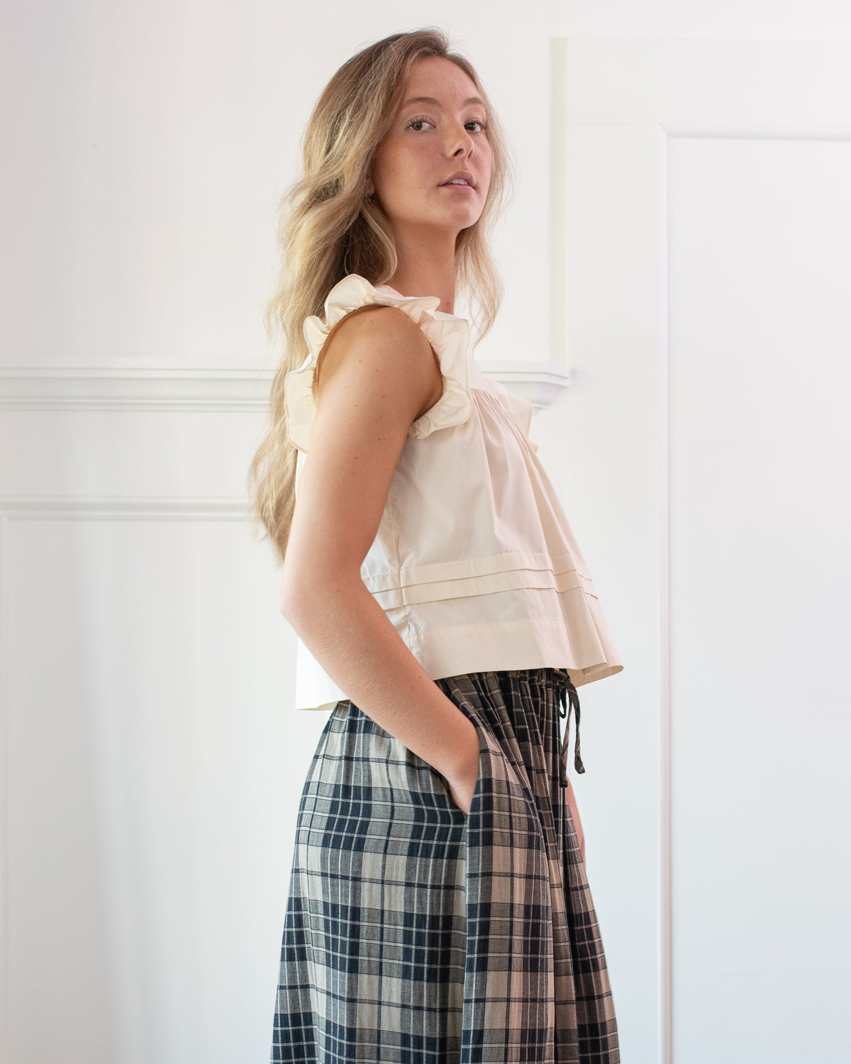 Cream cotton cropped top with pintuck hem styled with a plaid skirt, feminine vintage inspired, side view.