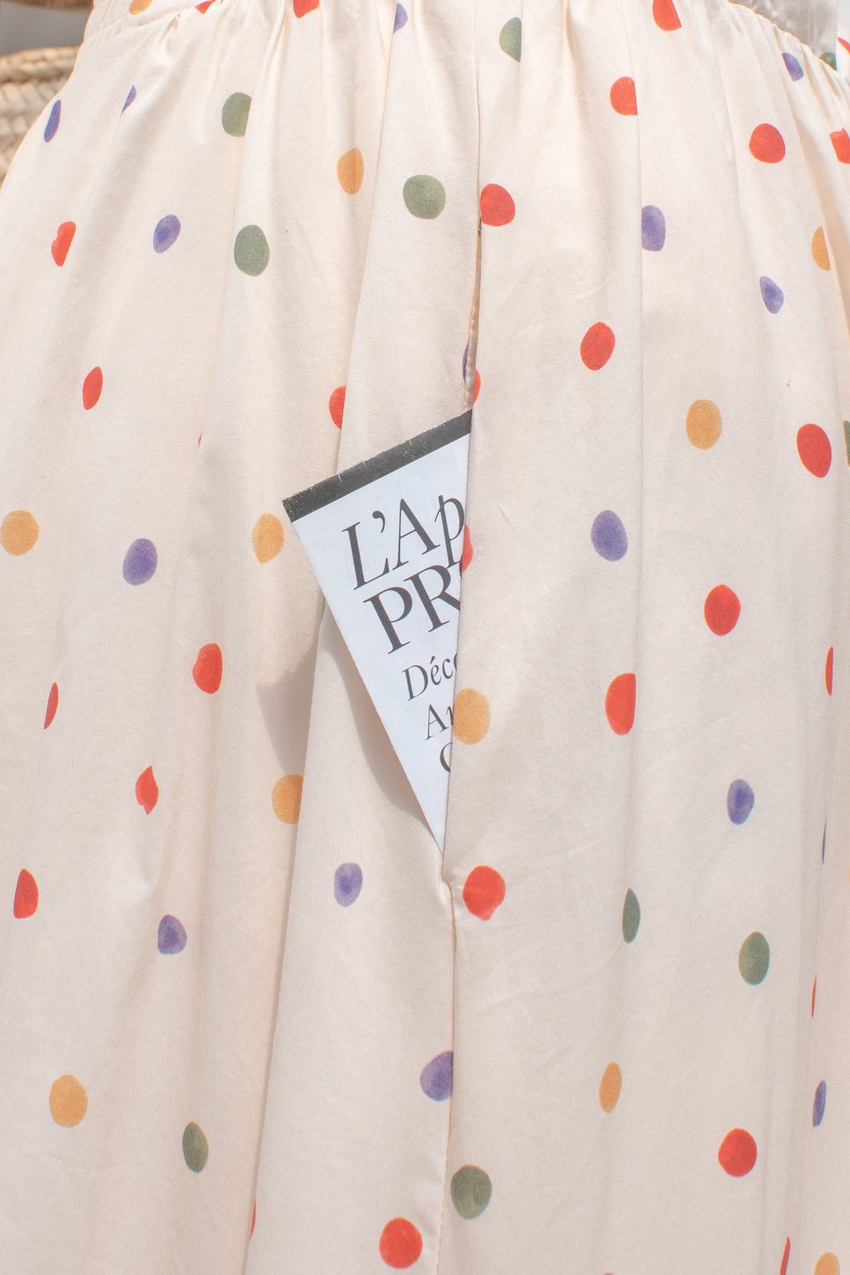 Cream cotton fabric with multicolored  polka dot print and pockets close up.