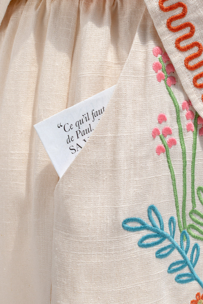 feminine clothing - a very unique summer set featuring a short sleeve button down shirt and shorts. In cream linen blend, it features very cute embroidery including a horse, and florals. A beautiful choice for your summer getaways. up close pocket and embroidery view. amantine french style clothing. 