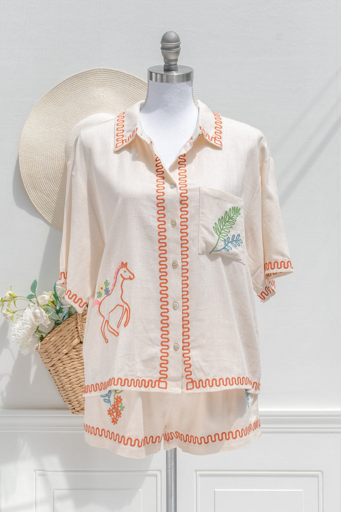 feminine clothing - a very unique summer set featuring a short sleeve button down shirt and shorts. In cream linen blend, it features very cute embroidery including a horse, and florals. A beautiful choice for your summer getaways. Front view. amantine french style clothing. 