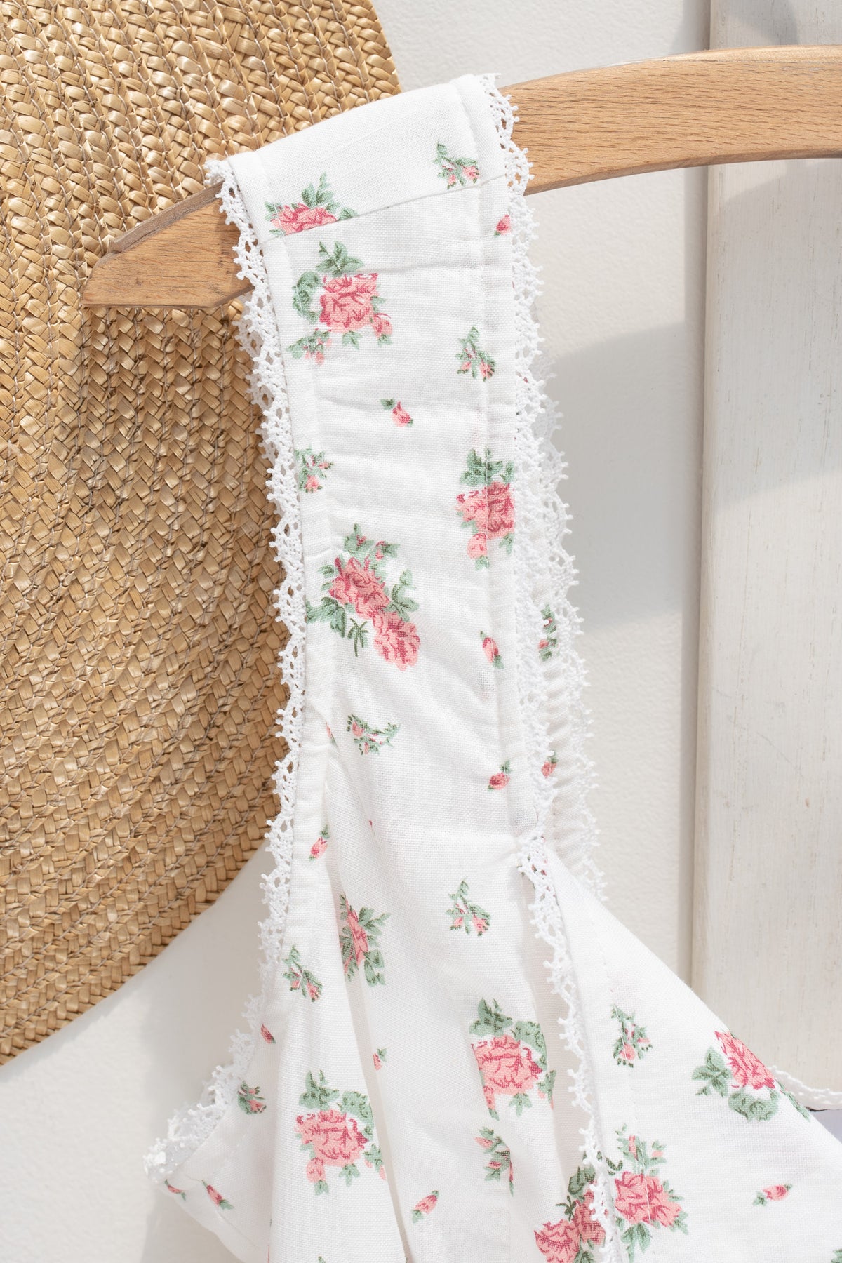 Close up of ruched lace trimmed strap detail on white floral linen cotton bustier top.