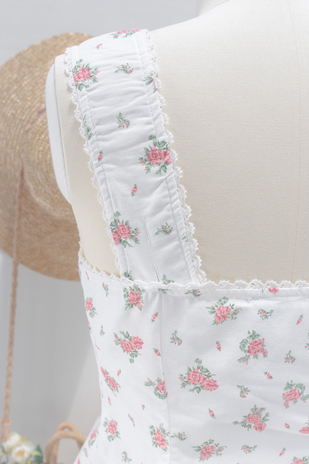 Close up of ruched lace trimmed strap and back neckline detail on white floral linen cotton top.