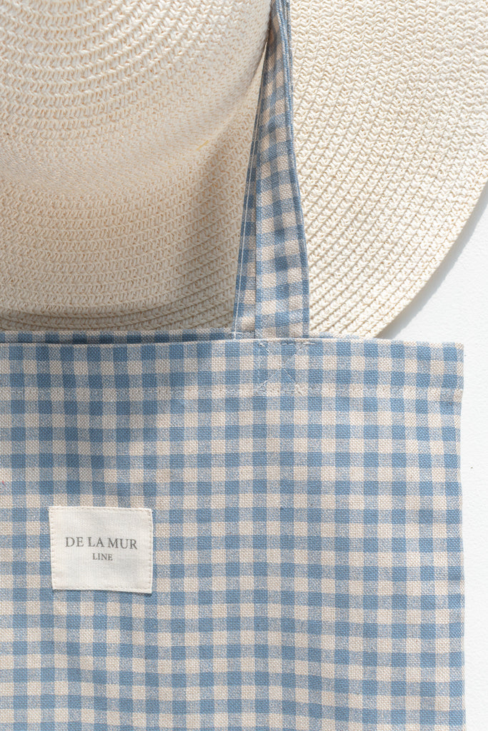 Blue and white checkered bag with a straw hat on a white background