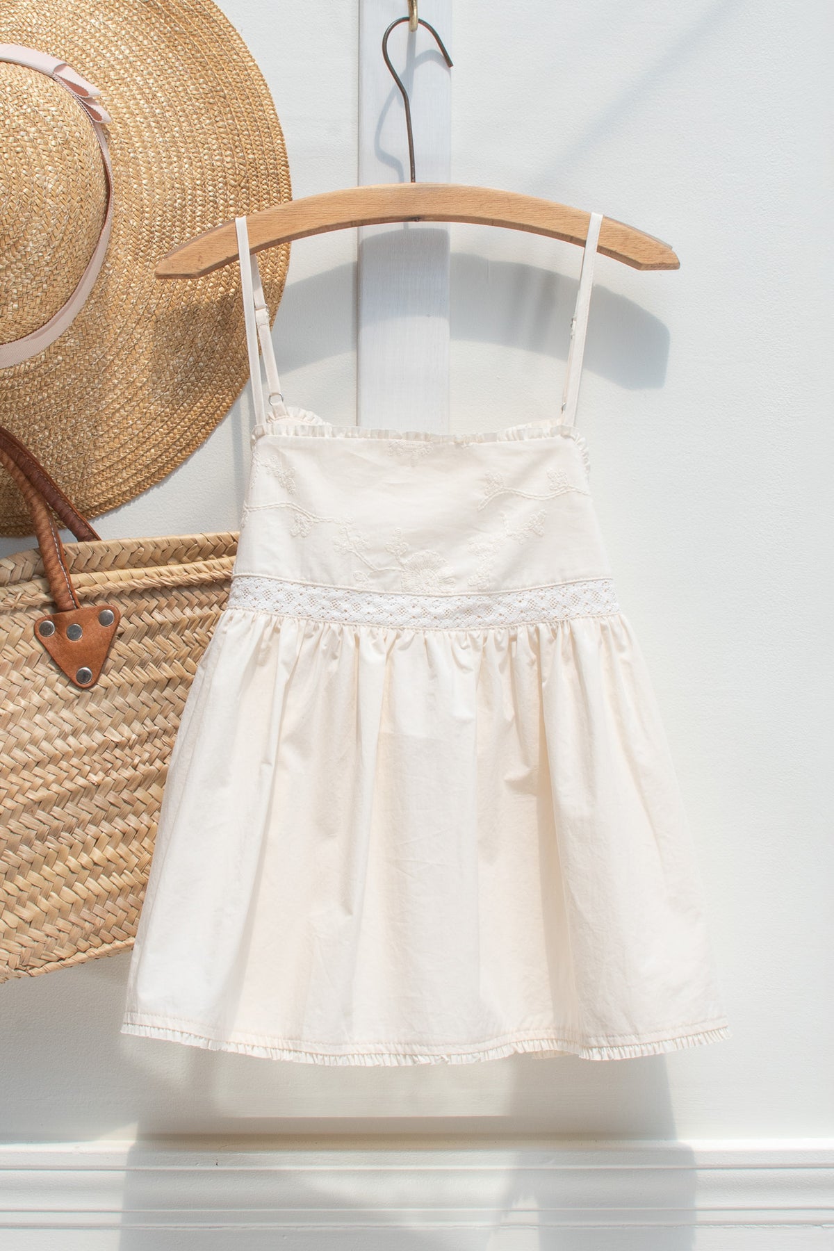 Ivory cotton embroidered babydoll top shown on a hanger, front view.