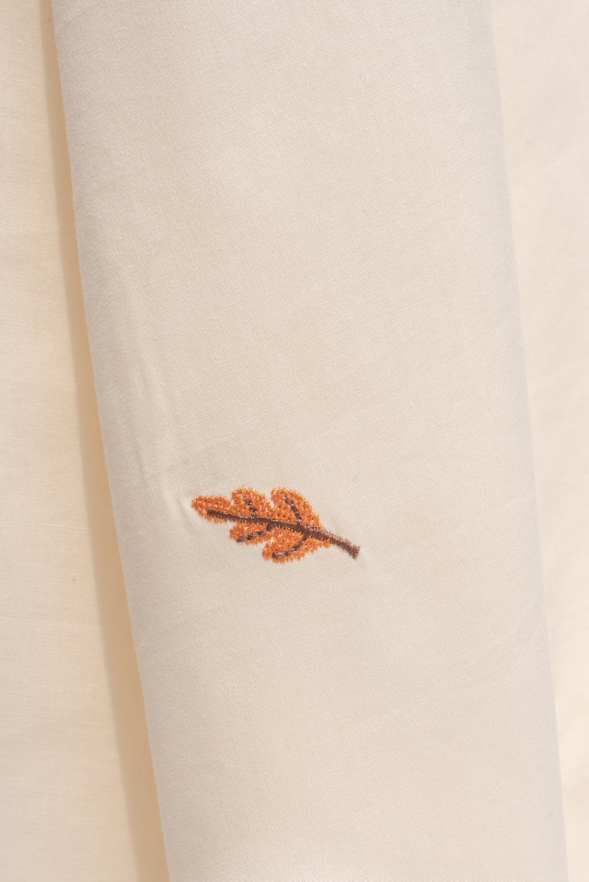 Close up detail of embroidered leaf stitching on ivory cotton fabric from the midi dress.