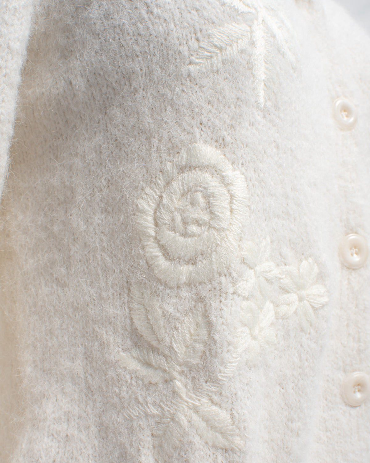 Ivory floral embroidered cardigan with rose detail, close mannequin view.