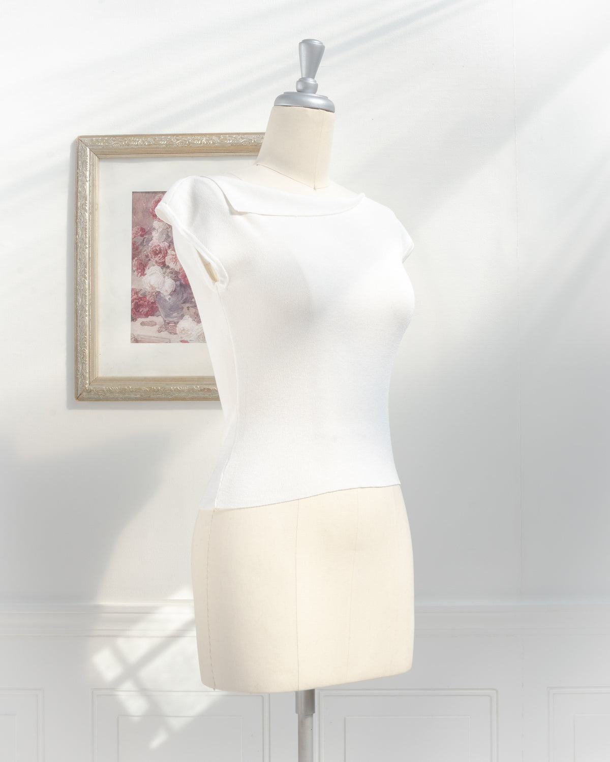 Ivory knit top with foldover boat neckline and cap sleeves on a mannequin, feminine classic style, three quarter view.
