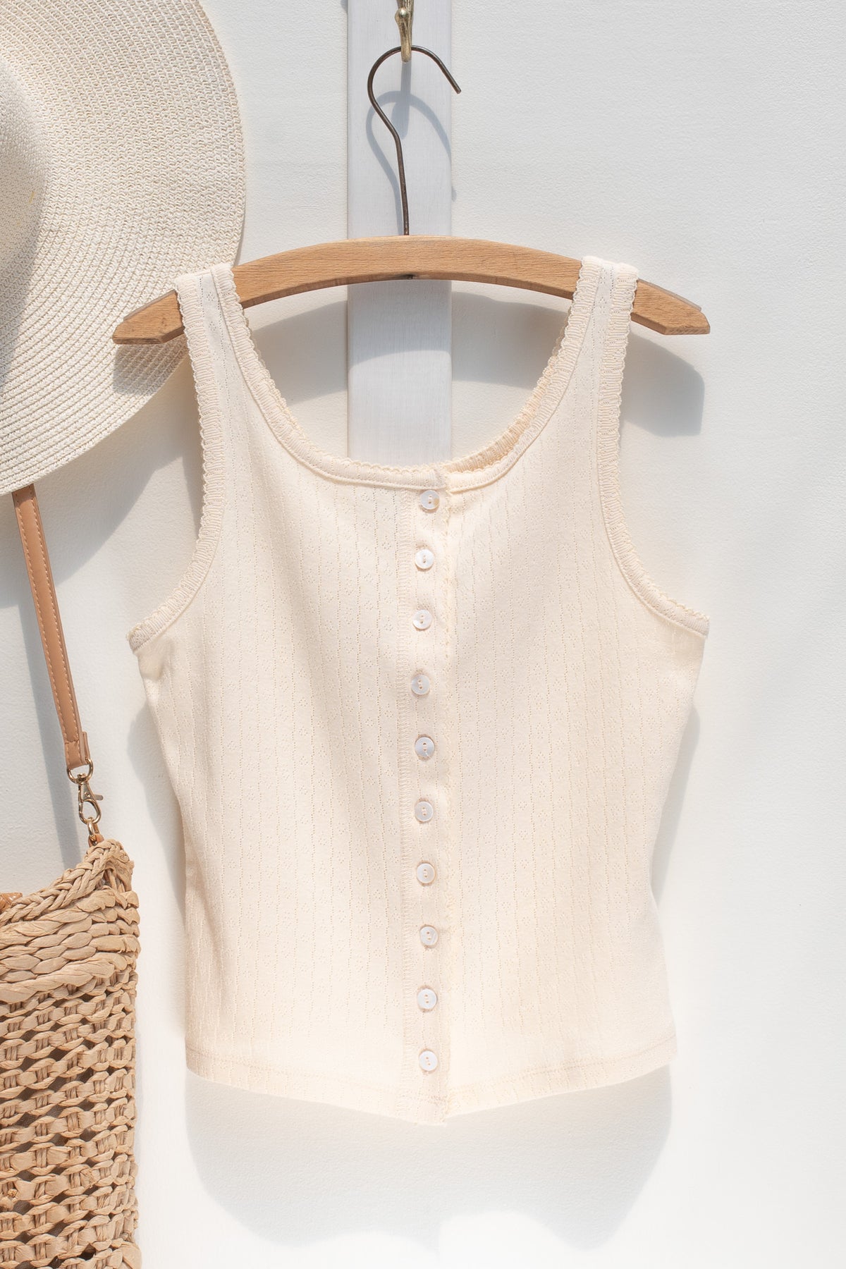 Ivory pointelle knit tank top shown on a hanger, front view.