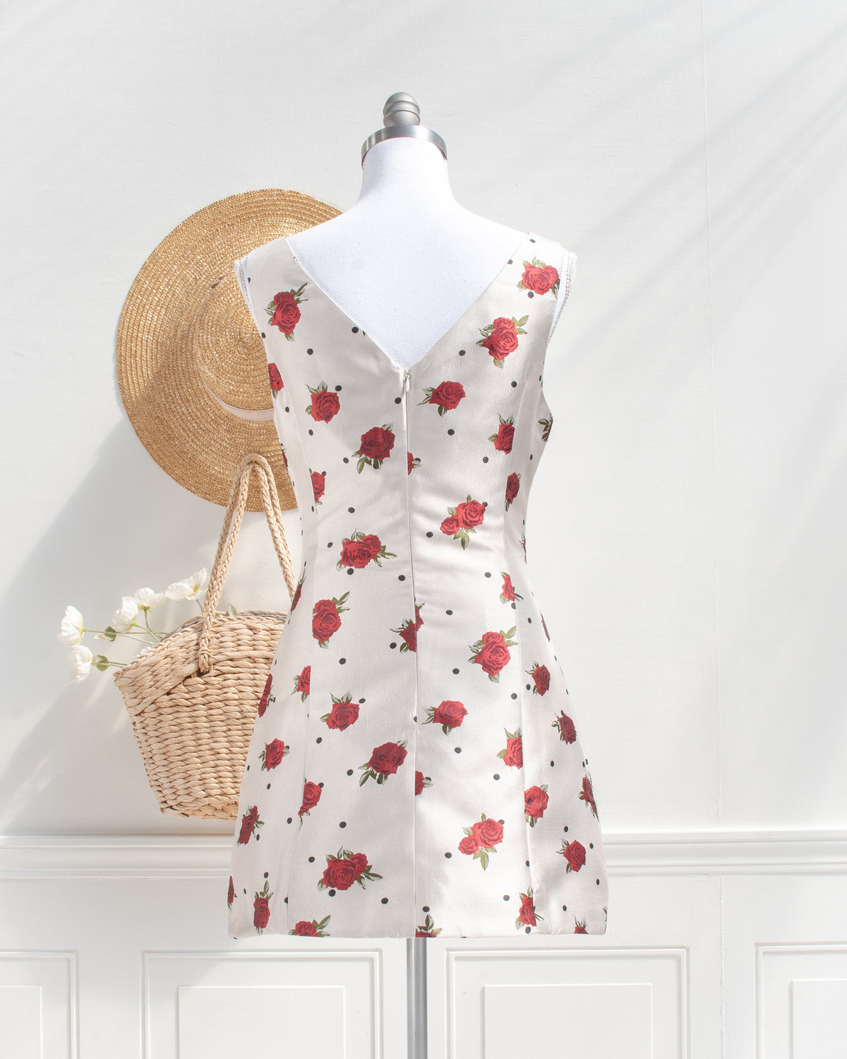 Ivory rose and polka dot mini dress with a V back and center back zipper on a mannequin, back view.