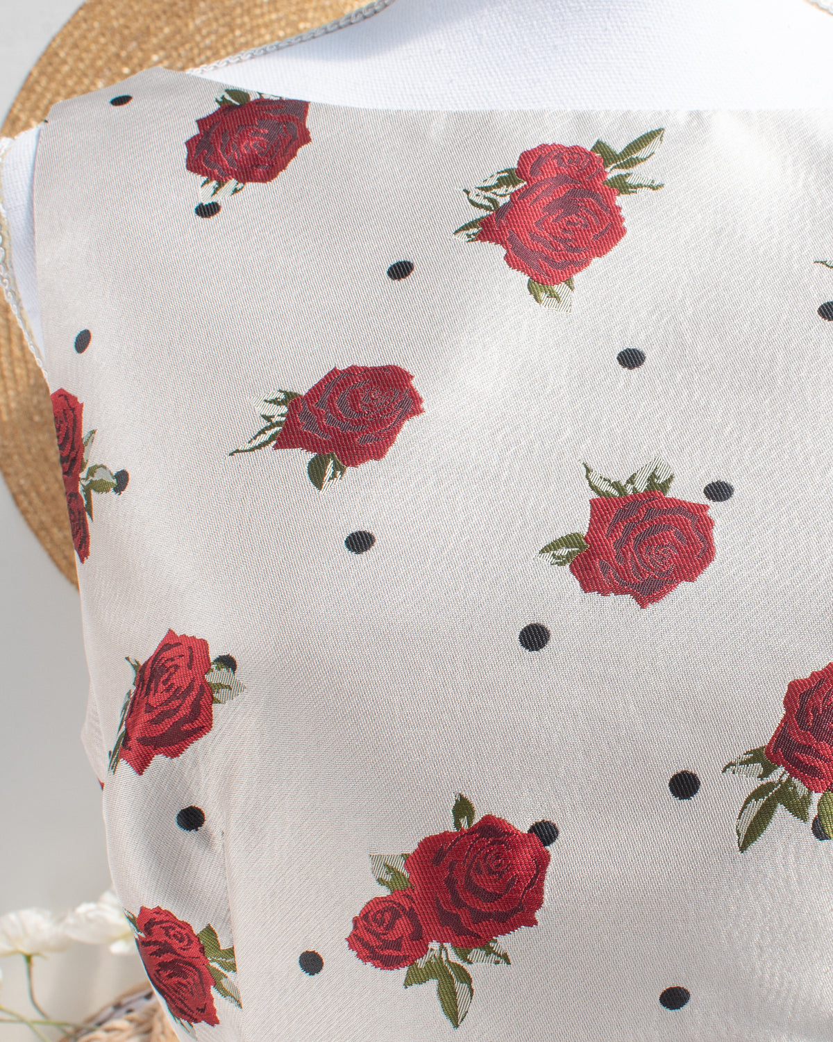 Ivory mini dress with a red rose and black polka dot print and a boat neckline, front detail view.