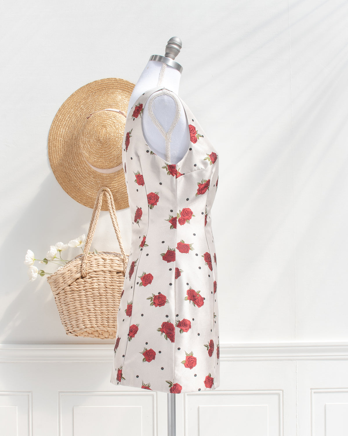 Ivory sleeveless rose and polka dot mini dress with a fitted waist on a mannequin, side view.
