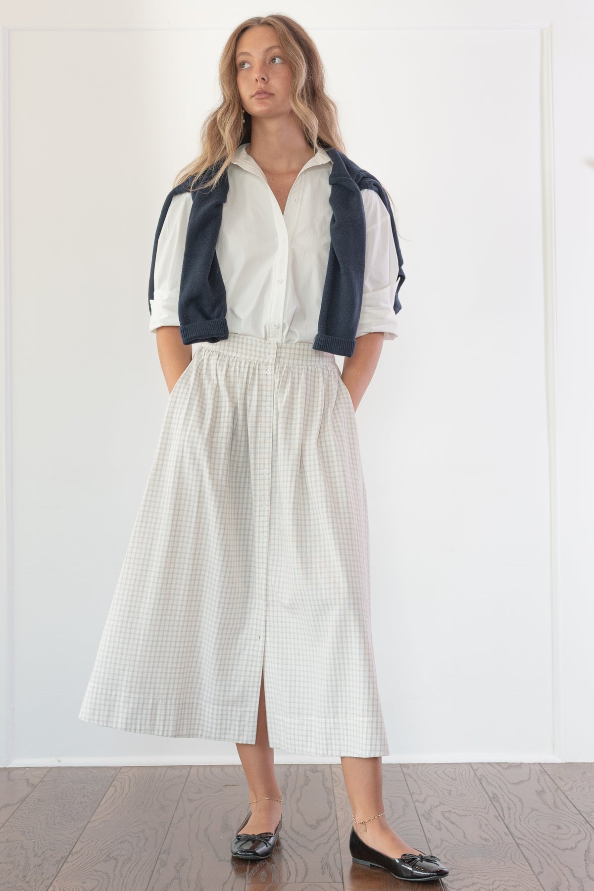 Navy cotton wool cropped cardigan worn open over a white blouse, a timeless wardrobe essential.