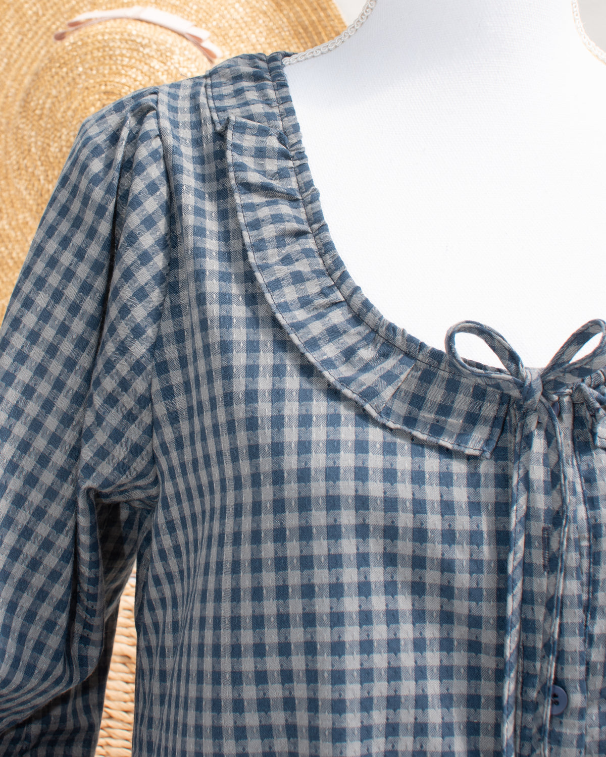 Navy gingham mini dress with ruffled collar and tie front, close mannequin view.