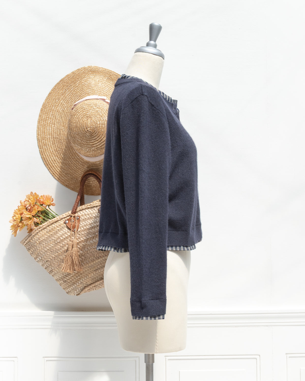 Navy knit cropped cardigan with plaid trim at the hem and cuff, mannequin side view.