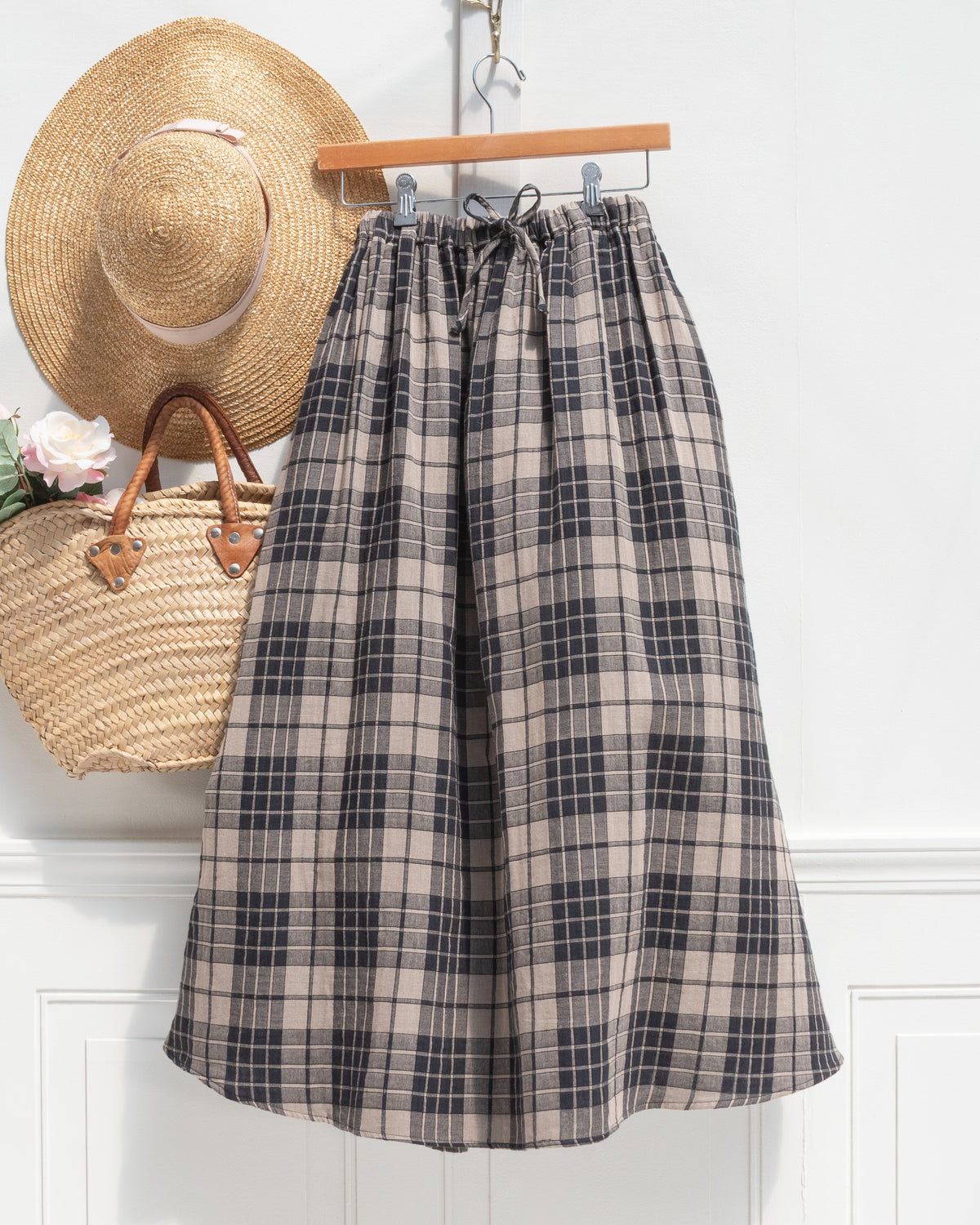Tan and black plaid cotton midi skirt with drawstring waist shown on a hanger, front view.