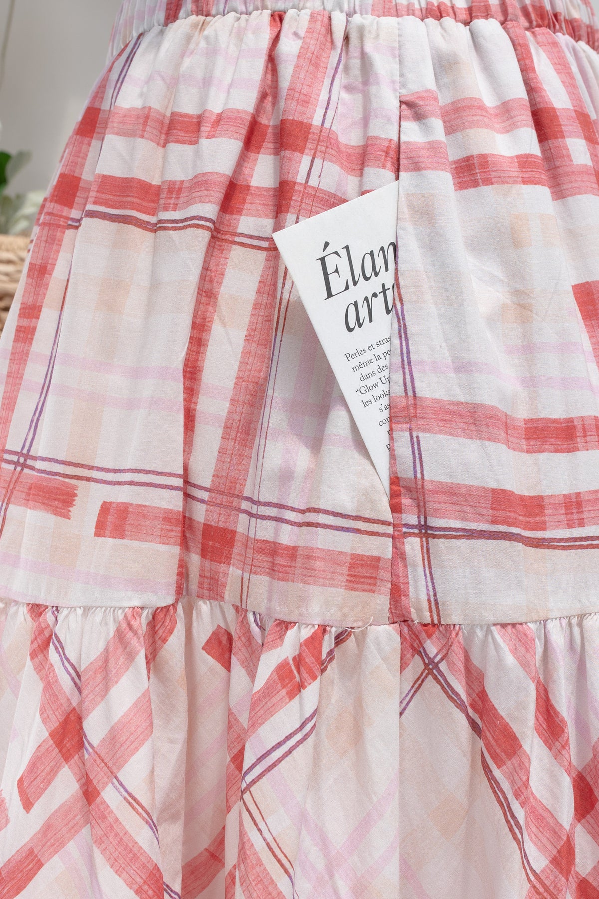 Red and pink plaid cotton midi skirt showing side seam pocket and tier seam detail.