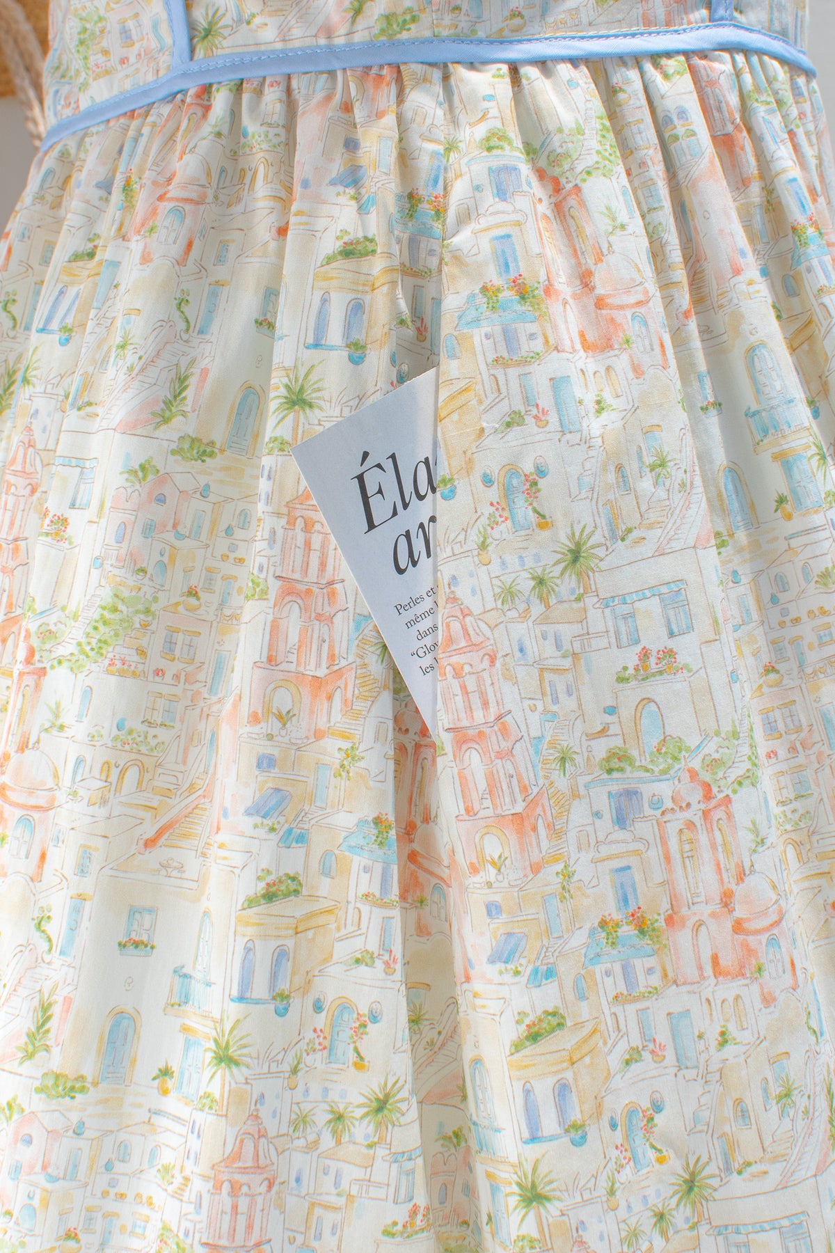 Close up of watercolor cityscape toile print and periwinkle blue waist trim detail.