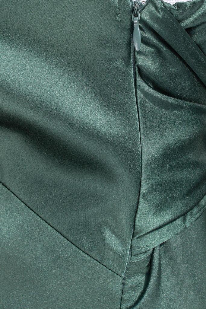 Beautiful wedding guest and formal dress in emerald green. French style feminine and romantic dress with straps, slit, and a bow. zipper view. Amantine dresses. 