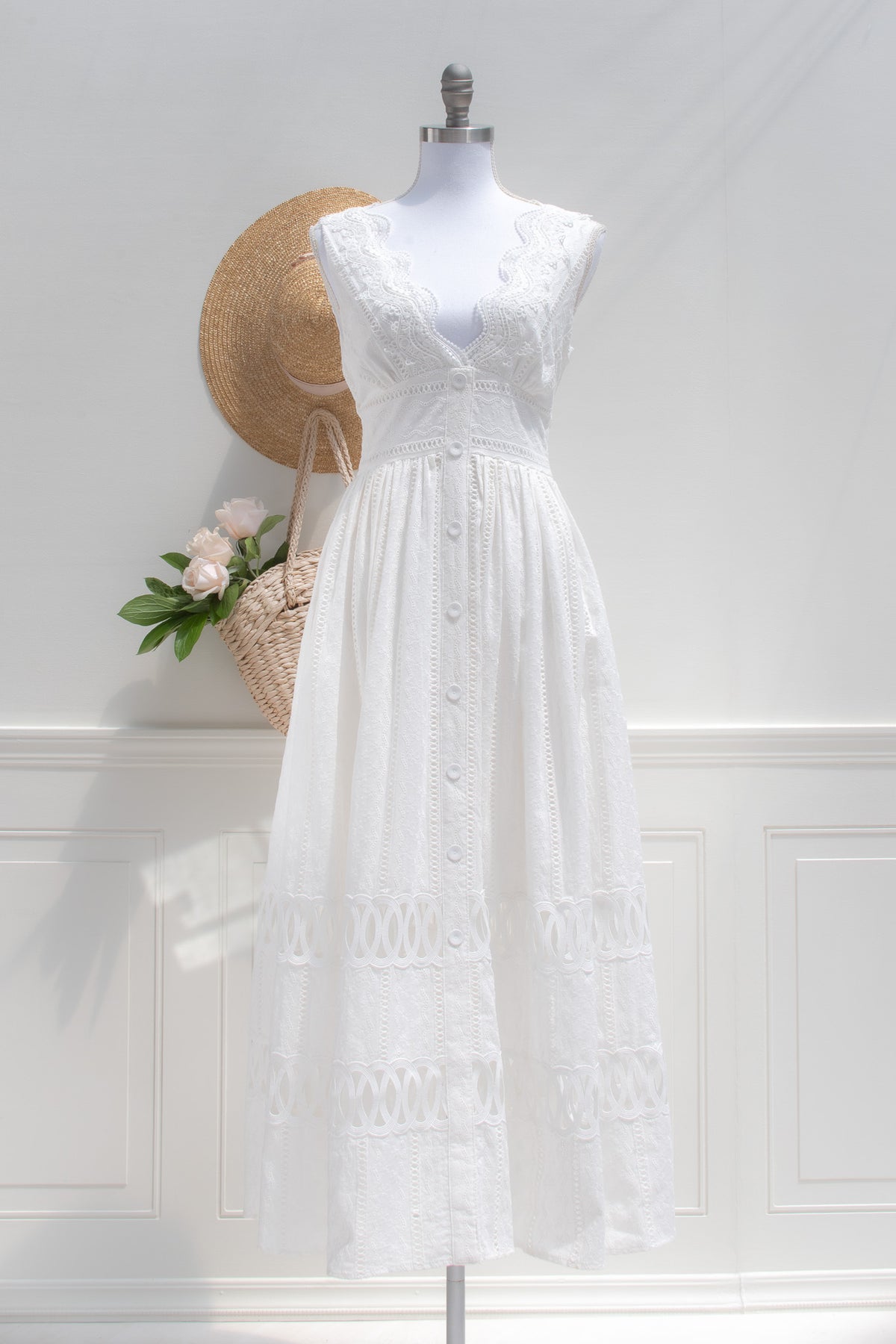 White cotton eyelet midi dress with V-neckline and button front on a dress form