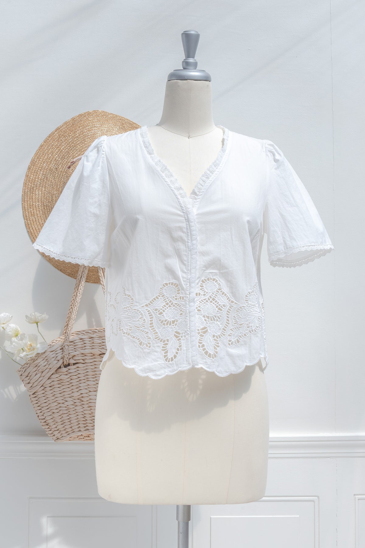 White cotton cropped blouse with puff sleeves and cutwork lace hem, front view.