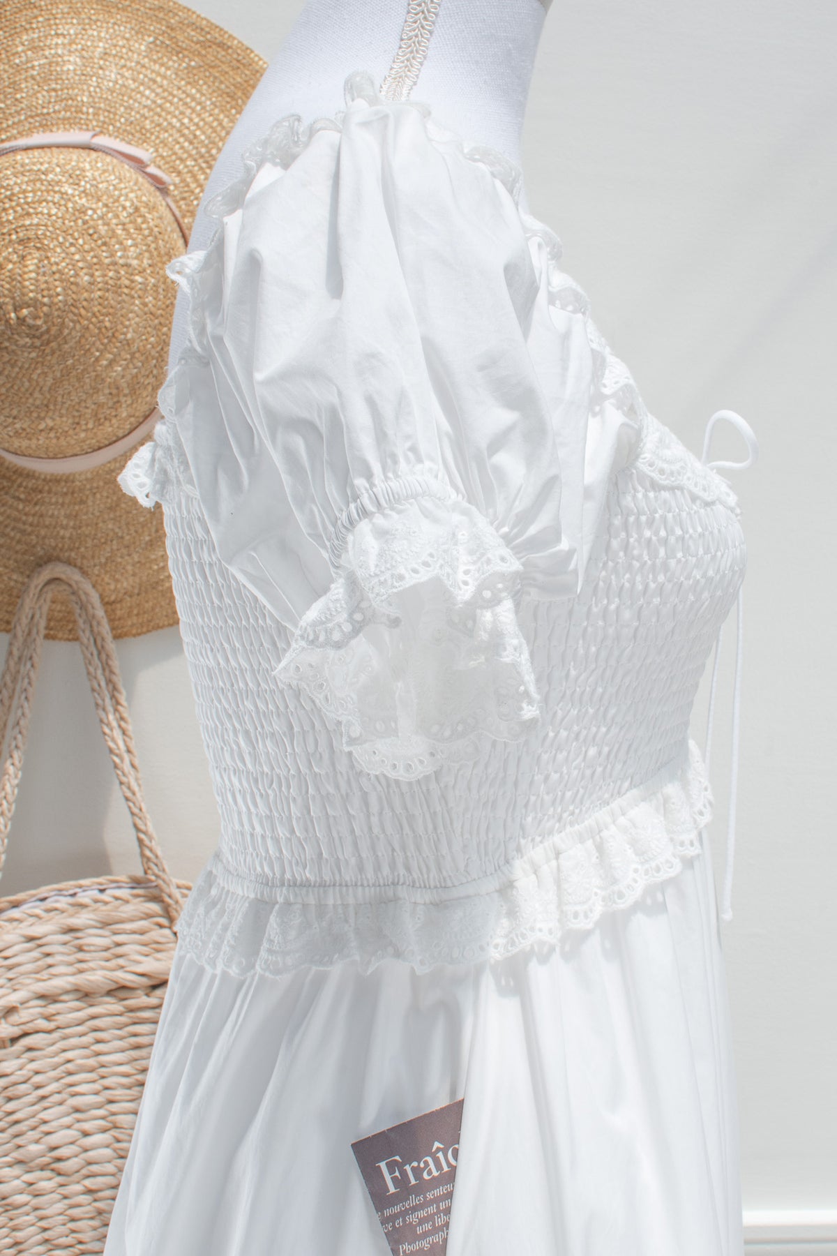 White cotton midi dress with ribbon tie neckline and smocked bodice detail closeup.