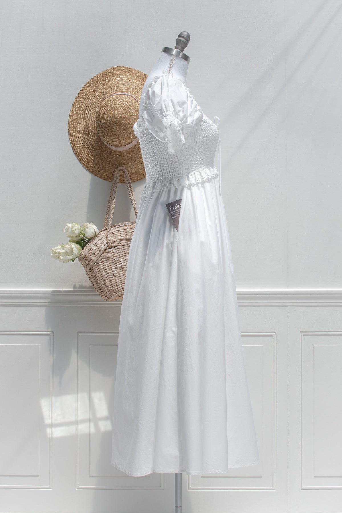 White cotton midi dress with smocked bodice and puff sleeves, side view.