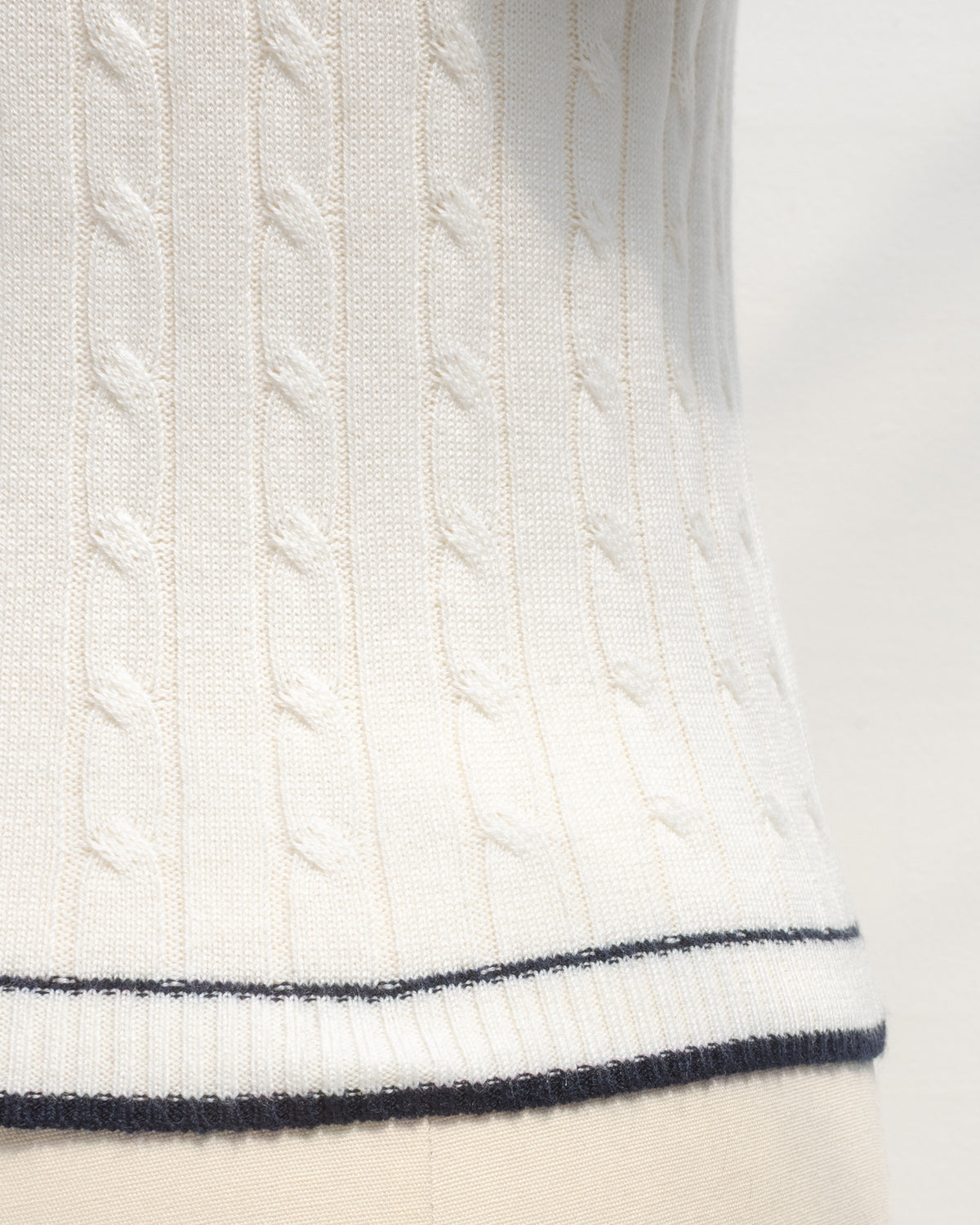 White cable knit sailor top with navy trim at the hem, close detail view.