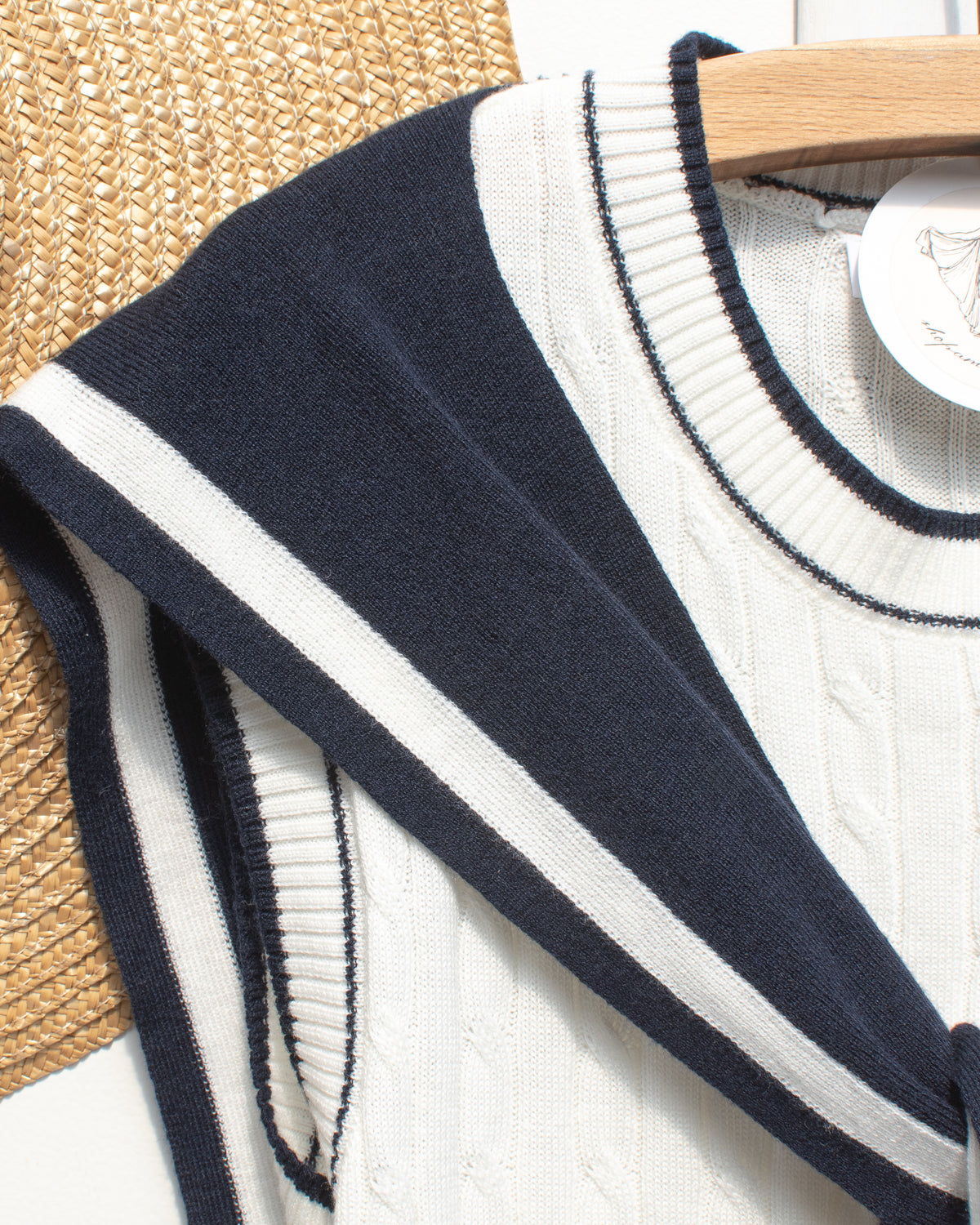 White cable knit sailor top with navy collar and ribbed neckline, close hanger view.