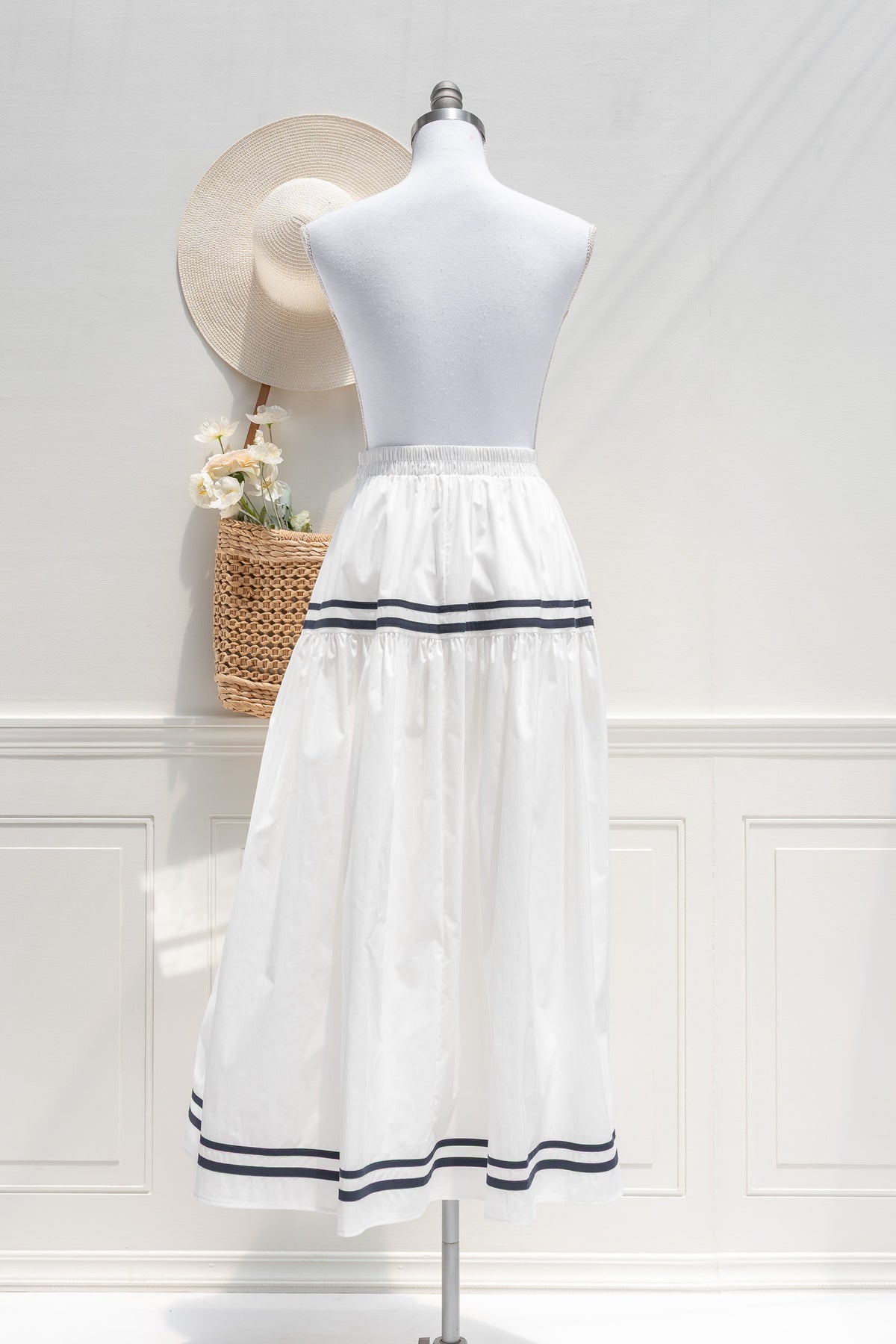 White cotton tiered midi skirt with navy stripe hem trim and elastic waist, back view.