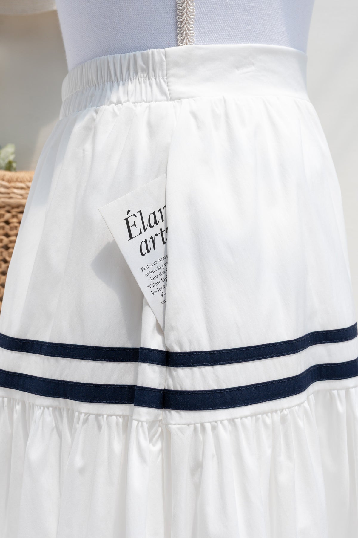 White cotton midi skirt showing side seam pocket and elastic waistband detail.