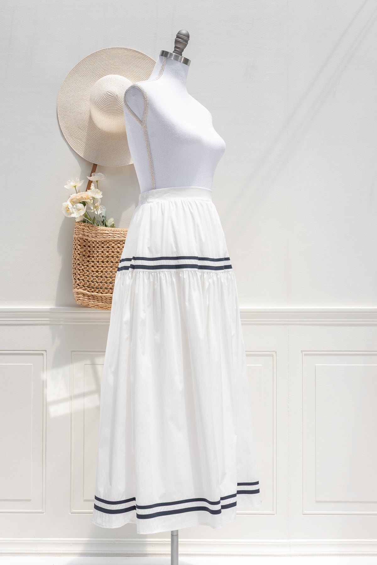 White cotton midi skirt with navy stripe trim and full tiered skirt, three quarter view.
